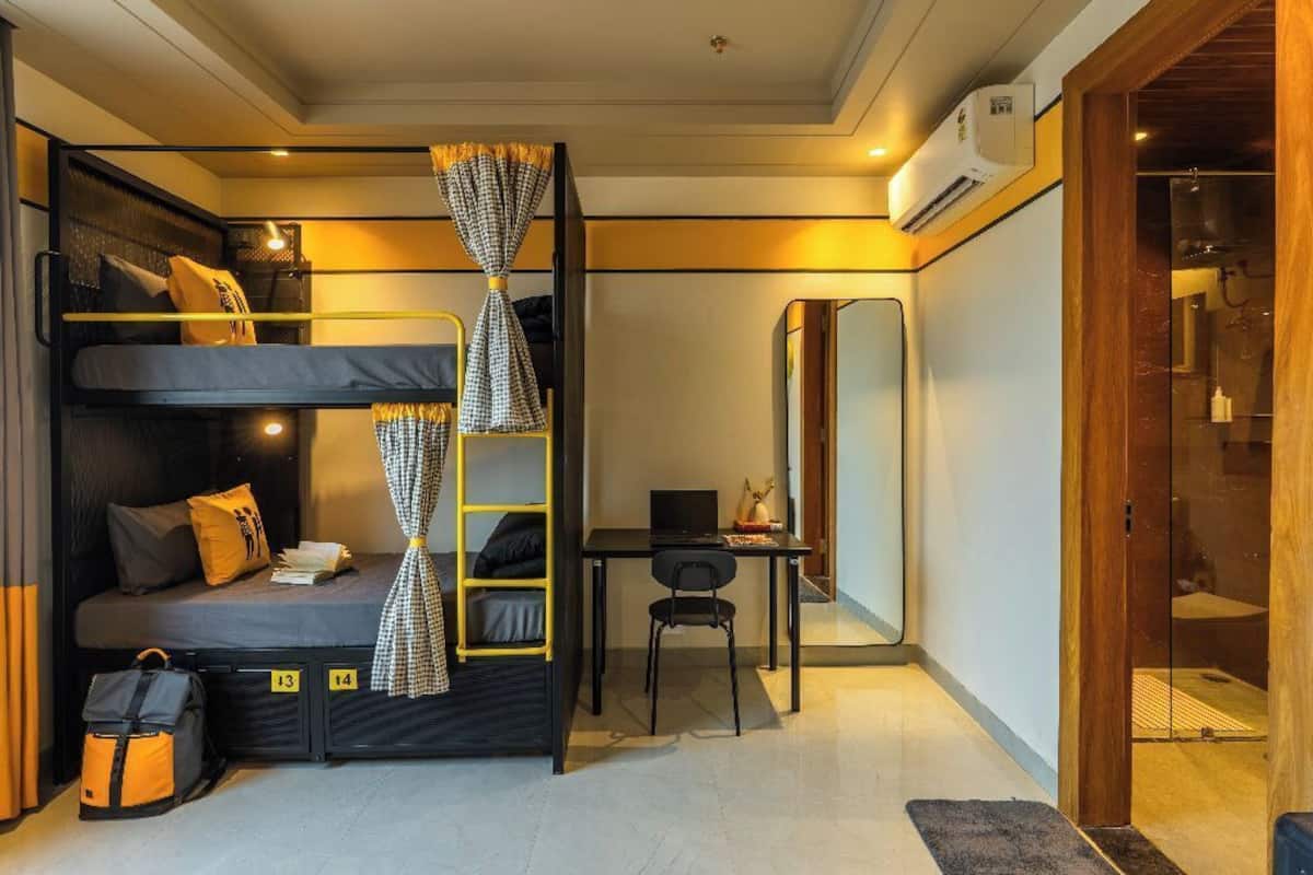 Une petite pièce avec des lits superposés, un bureau et un miroir.