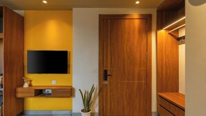 A modern interior with a wooden door, a mounted TV, and a potted plant. - The Hosteller Delhi, International Airport (New Delhi)