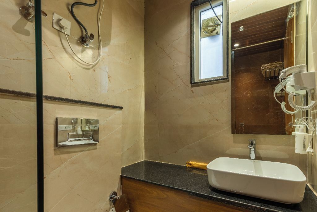 Ein Badezimmer mit Marmorwand, Waschbecken, Spiegel und Duschbereich.