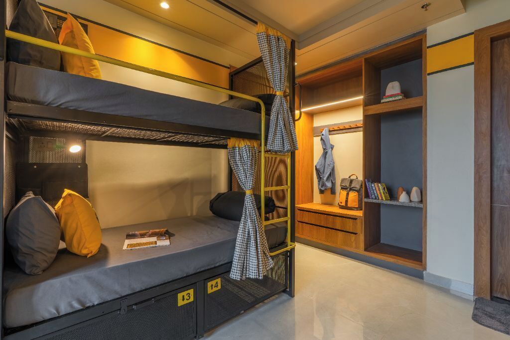 Une chambre avec un lit superposé, un petit bureau et des étagères.