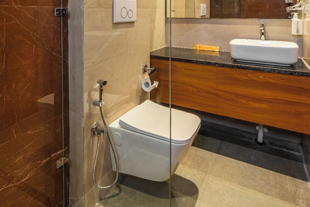 A modern bathroom with a glass-enclosed shower, a white toilet, and a wooden vanity with a sink.