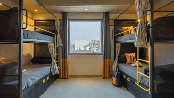 Una habitación de hotel compacta con dos literas, un ventanal grande y cortinas.
