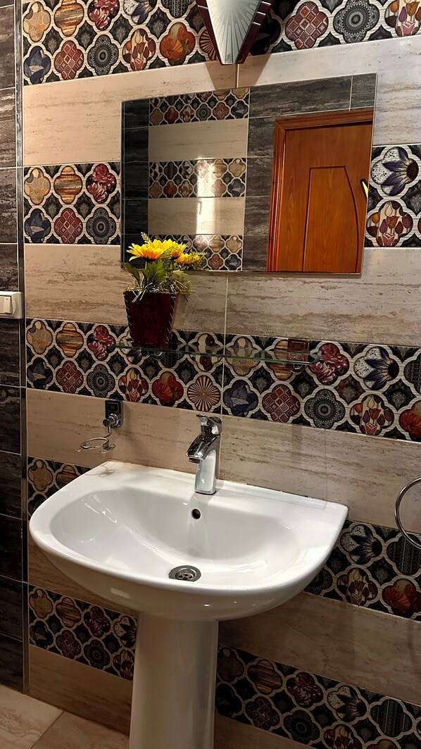 A bathroom with a white sink, a mirror, and a wooden door. - Pyramids Gold Sand INN (Giza)