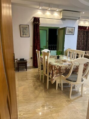 A dining area with a table, chairs, a potted plant, and an air conditioning unit. - Pyramids Gold Sand INN (Giza)