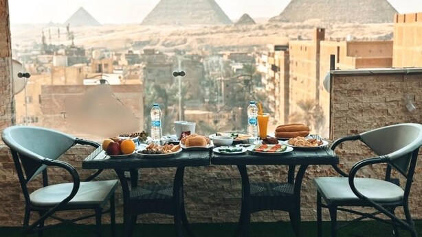 Une table dressée avec des aliments pour le petit-déjeuner, offrant une vue sur les pyramides.