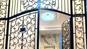 L’entrée d’un hôtel, avec un escalier en marbre menant à une porte dotée d’un panneau en verre.
