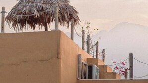Un edificio con tetto di paglia, un balcone con ringhiera e una porta che dà su uno spazio interno.