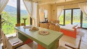 Un'ampia sala da pranzo con un lungo tavolo, sedie e vista su un paesaggio rigoglioso.
