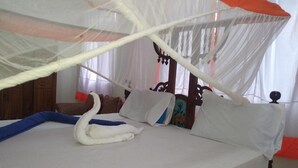 Uma cama com dossel, almofadas e um arranjo de travesseiros em formato de cisne.
