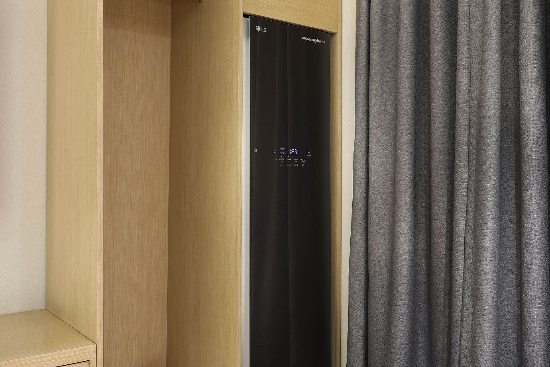 Una habitación con un armario de madera, un electrodoméstico negro y cortinas grises.