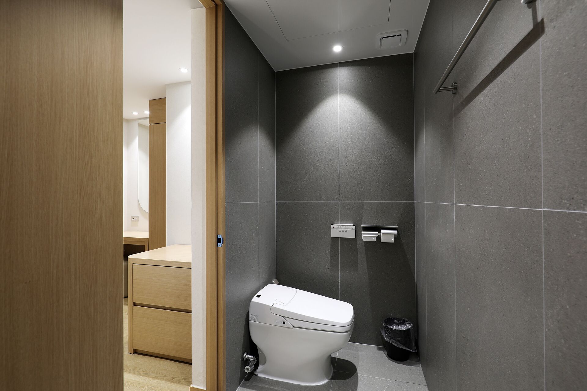 Un baño moderno con inodoro, ducha y un mueble de madera.