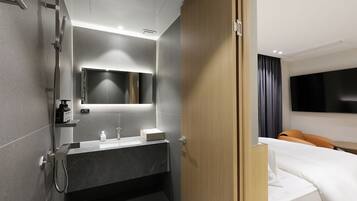 A modern hotel bathroom with a shower, sink, and mirror.