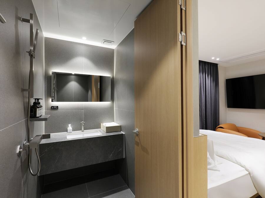 A modern hotel bathroom with a shower, sink, and mirror.