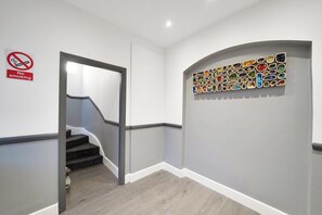 Un couloir avec un panneau « Il est interdit de fumer », un escalier et un mur orné d’une mosaïque colorée.