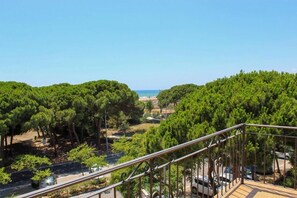 A balcony with a metal railing overlooking a coastal area with dense green trees and a clear blue sky. - Hotel Rodsan (Castelldefels)