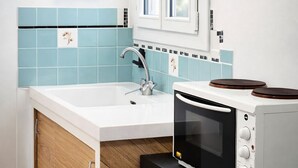 Eine moderne Küche mit einem weißen Spülbecken, blauen Fliesen, einer Mikrowelle und Holzschränken.