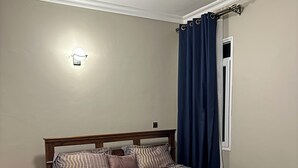 Ein Schlafzimmer mit einem hölzernen Bett, einem Nachttisch und einem Fenster mit Vorhängen.