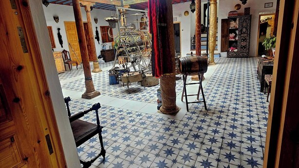 Un intérieur traditionnel avec un sol carrelé, des meubles en bois et une colonne décorative centrale.