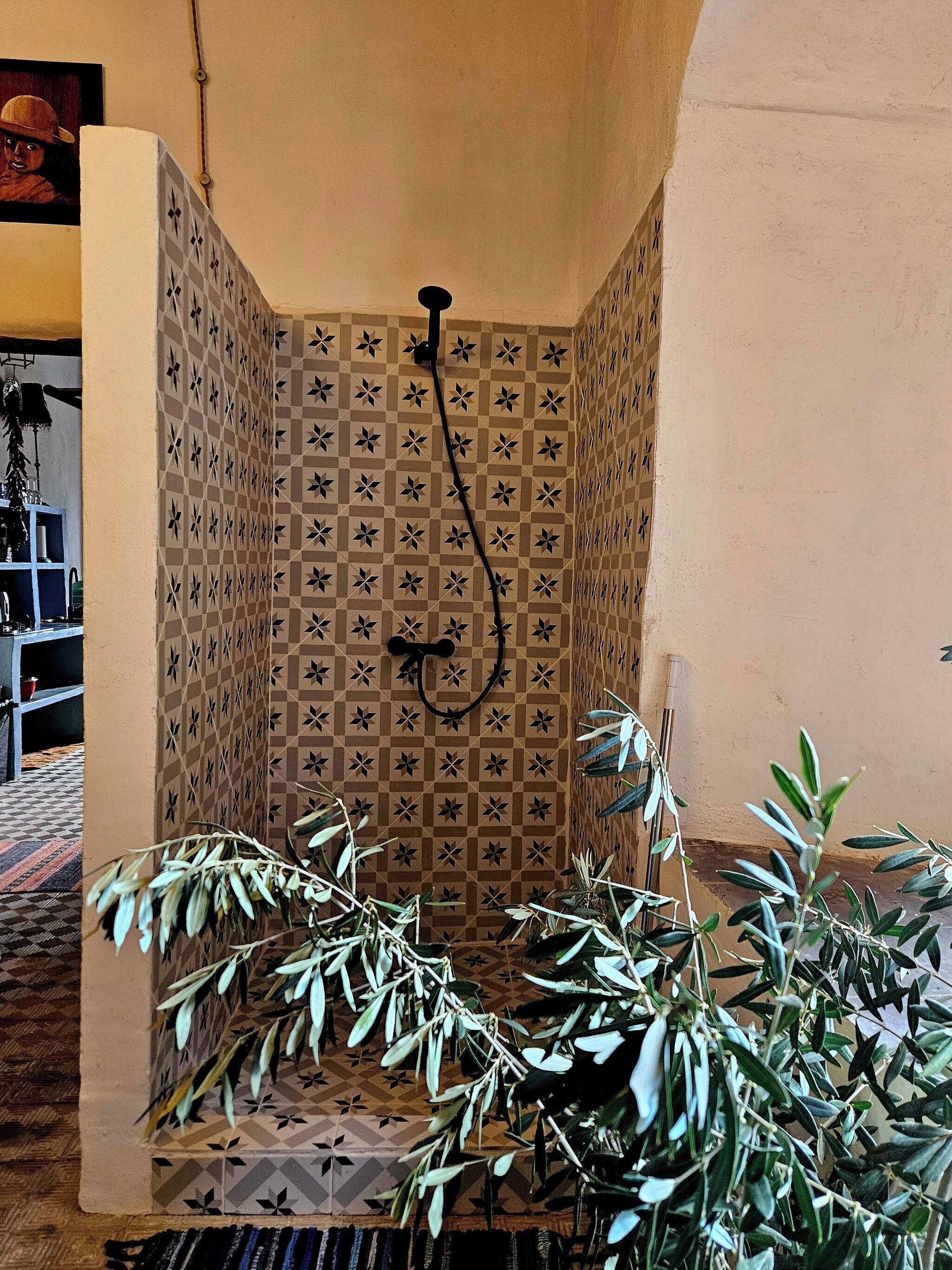 Ducha con un diseño geométrico de azulejos y un cabezal negro.