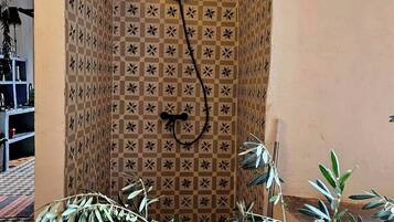 Ducha con un diseño geométrico de azulejos y un cabezal negro.