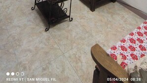 Habitació amb taula i cadires de fusta, una cadira de metall, llit amb cobrellit floral i un quadre de girsols a la paret.