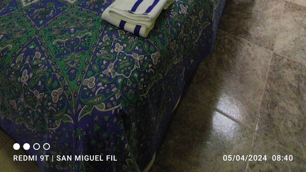 Une chambre avec deux lits, une table de chevet, une commode et une porte.