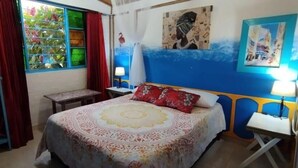 A bedroom with a bed, a nightstand, a window with curtains, and a wall with a painting. - Charming Guest Room Retreat in Quindio, Colombia (Filandia)
