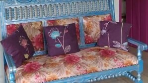 A room with a blue sofa with floral upholstery, a painting of a tropical landscape, and a wooden ceiling with a light fixture. - San Miguel Filandia 2 (Filandia)