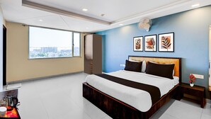 A modern hotel room with a large bed, a view of the city, and a small table with a coffee pot and cup. - Hotel Fortune Prime (Jaipur)