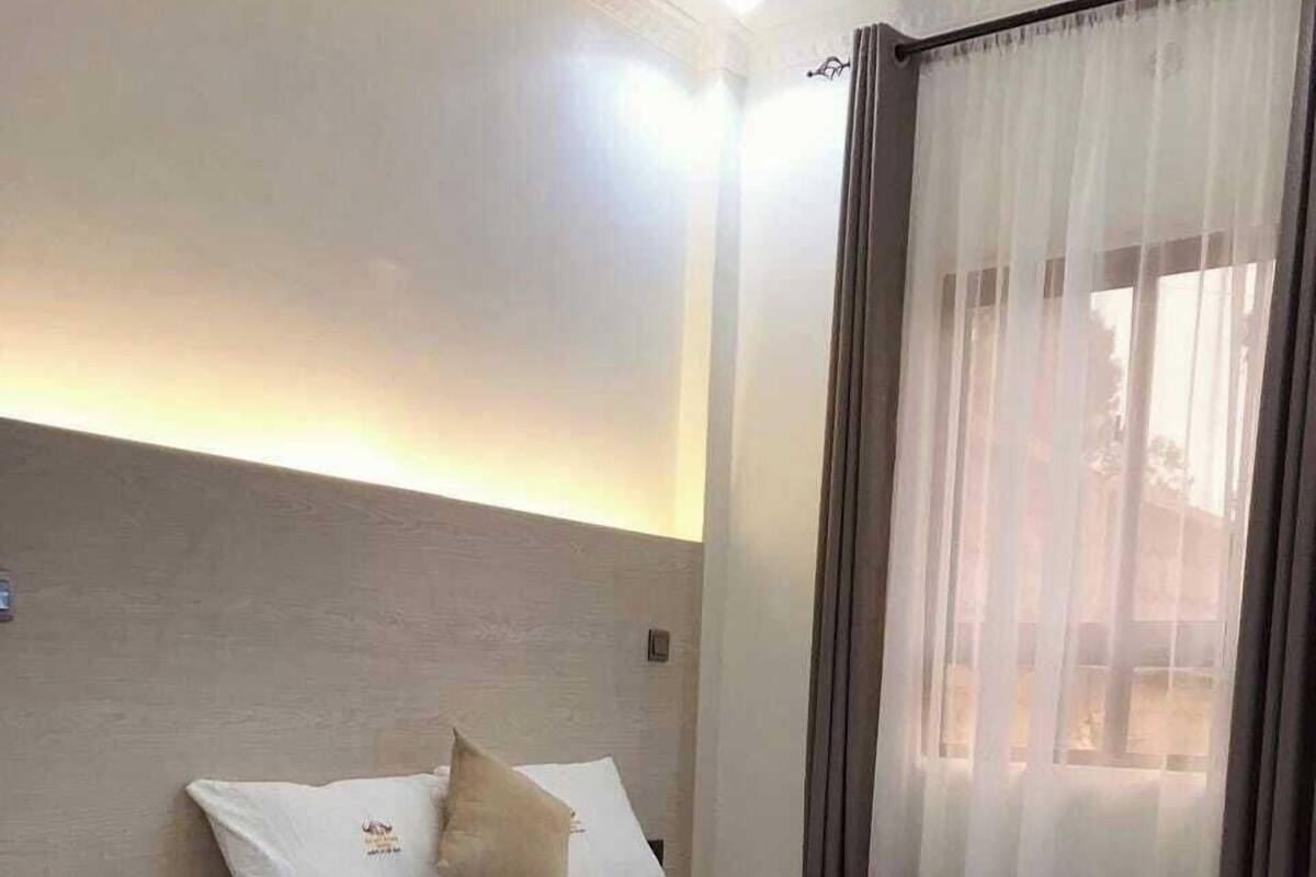A neatly arranged hotel room with a bed, bedside table, and a window with curtains.
