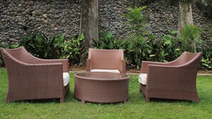 A wicker outdoor seating area with a round table and three chairs. - Ole Sidai Riverine Gardens (Karatina)