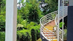 A spiral staircase leading to a covered area surrounded by lush greenery. - Ole Sidai Riverine Gardens (Karatina)