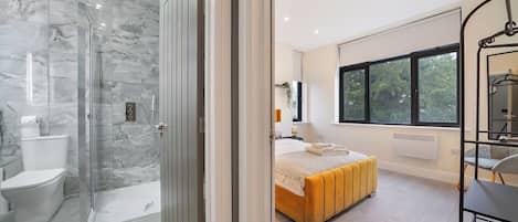 A modern bathroom with a glass shower enclosure and a toilet.