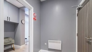 Ein Flur mit grauer Wand, einem weißen Heizkörper, einer geschlossenen Tür und einem Rauchverbot-Schild.