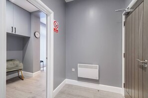 Ein Flur mit grauer Wand, einem weißen Heizkörper, einer geschlossenen Tür und einem Rauchverbot-Schild.