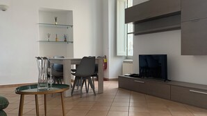 En moderne stue med spiseplads, et fjernsyn og en pejs.