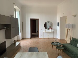A modern living room with a sofa, a coffee table, a TV, and a dining area. - Casa Bartolo apartment located in the historic center of Assisi (assisi)