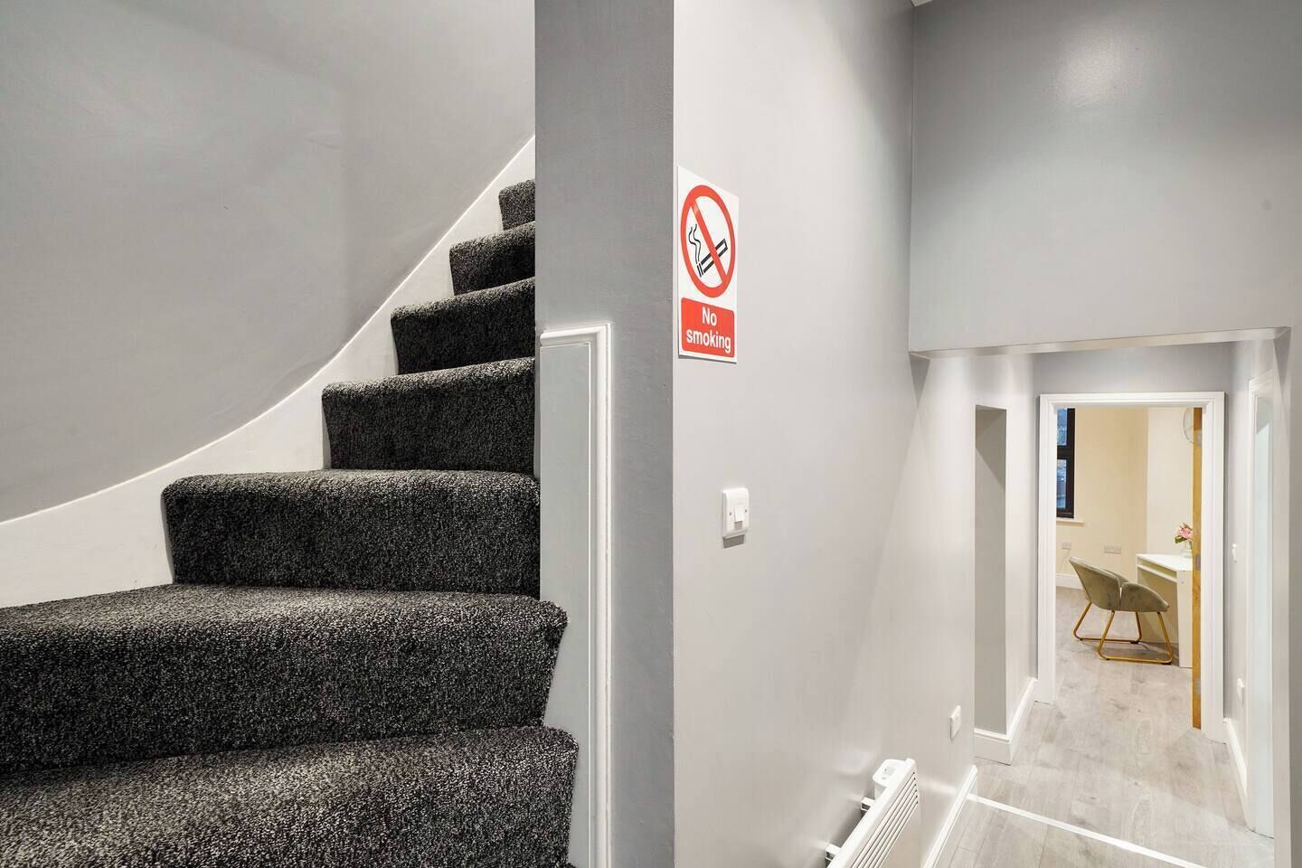 A staircase with a no-smoking sign, leading to a room with a desk and chair.