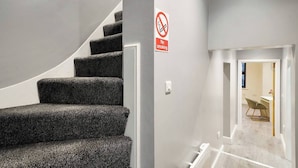 Una escalera con un cartel de prohibido fumar que lleva a una habitación con un escritorio y una silla.