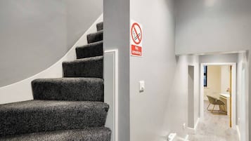 A staircase with a no-smoking sign, leading to a room with a desk and chair.