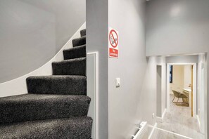 A staircase with a no-smoking sign, leading to a room with a desk and chair. - Modern & Cozy 3-Bed Apartment (London)