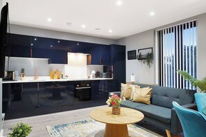 A modern living space with a kitchen, a sofa, and a coffee table. - Modern & Cozy 3-Bed Apartment (London)