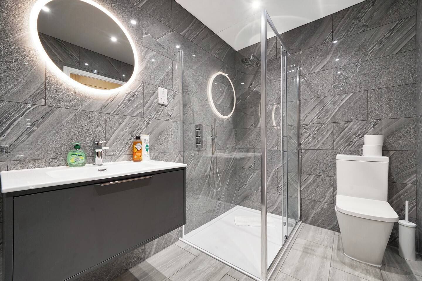 A modern bathroom with a glass-enclosed shower, a vanity with a mirror, and a toilet.