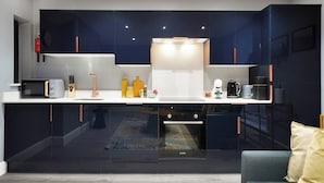 Una cocina moderna con armarios oscuros, encimera blanca y electrodomésticos de acero inoxidable.