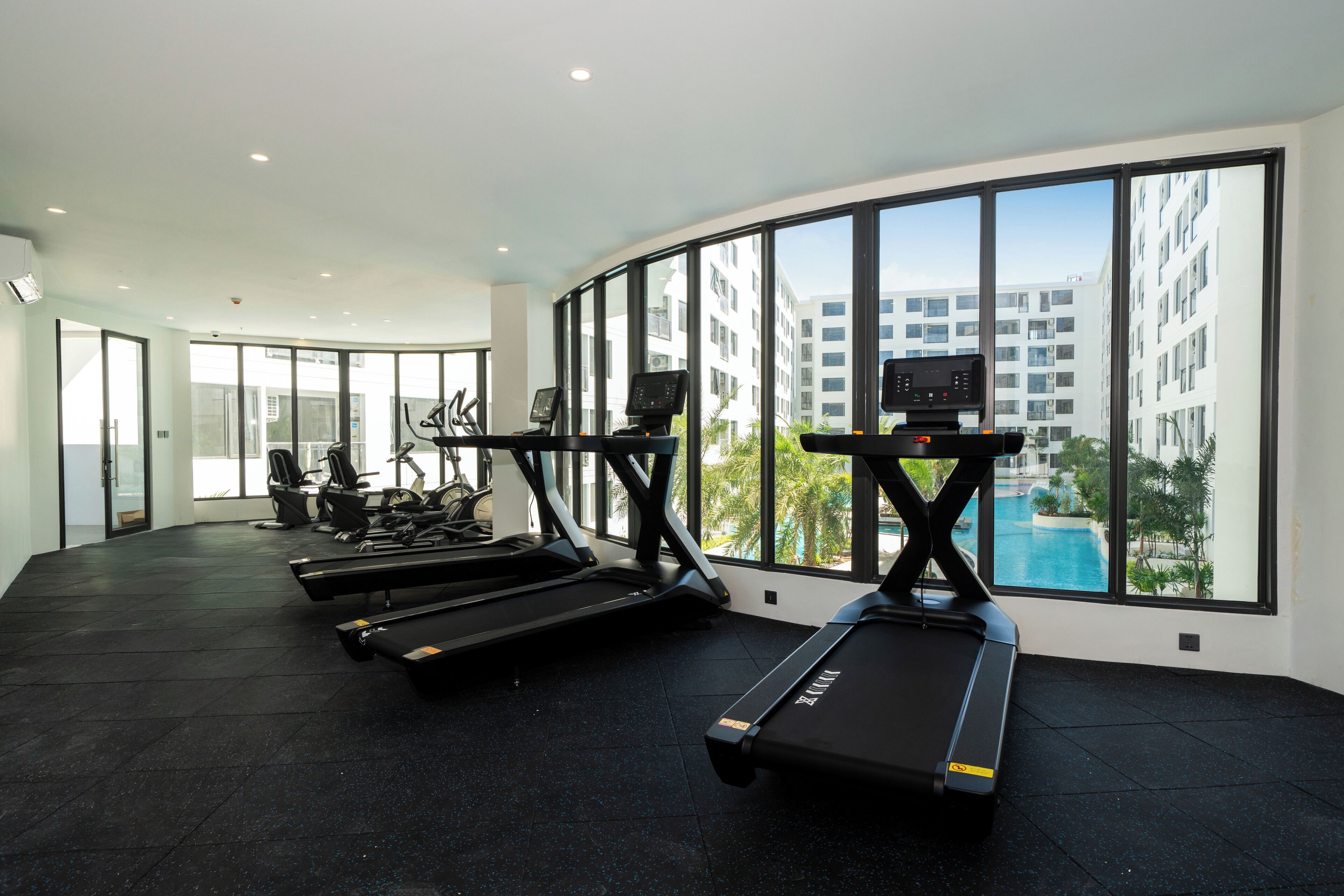 A modern gym with treadmills, stationary bikes, and elliptical machines.