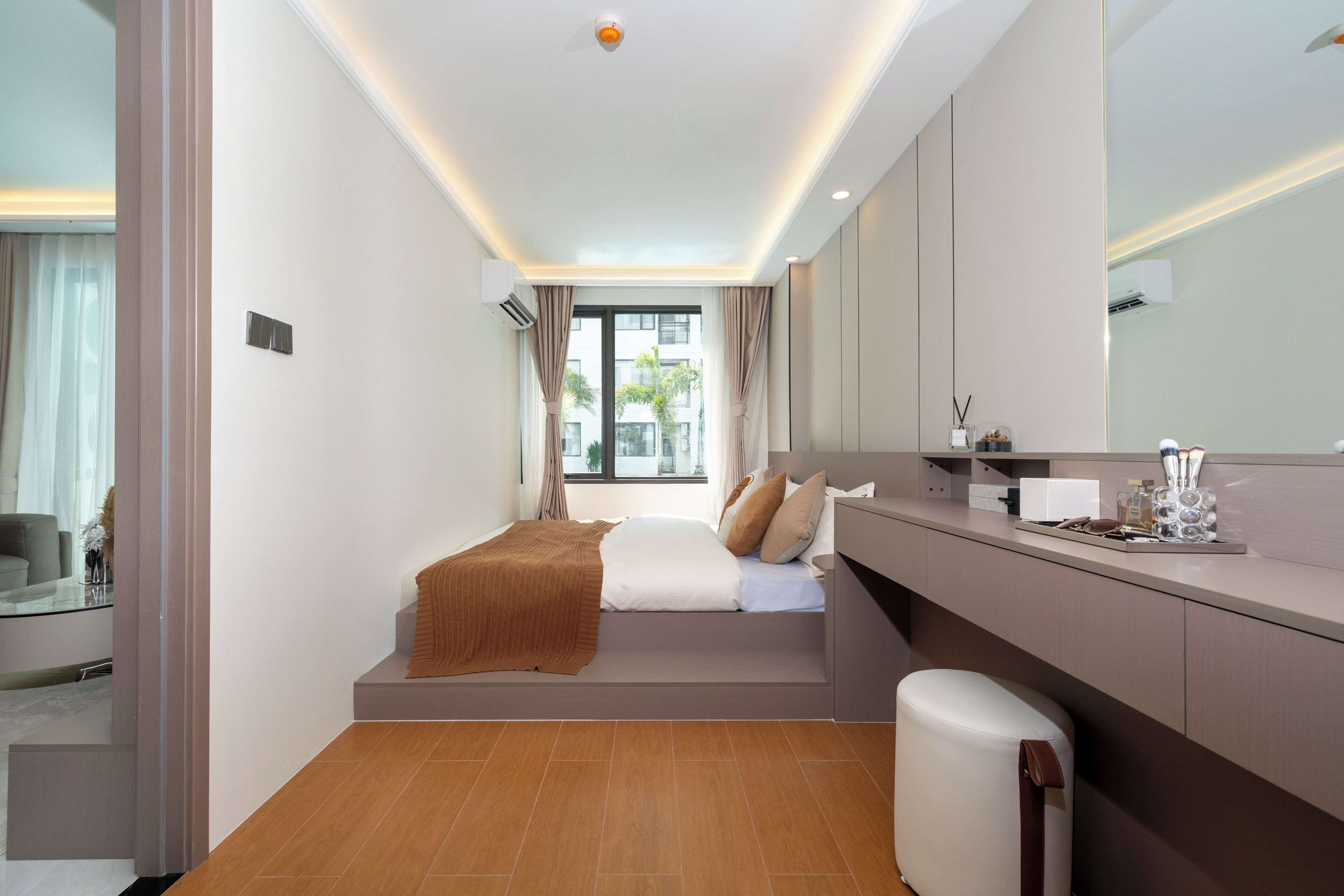 Een moderne hotelkamer met een bed, een kaptafel met spiegel en uitzicht op buiten.