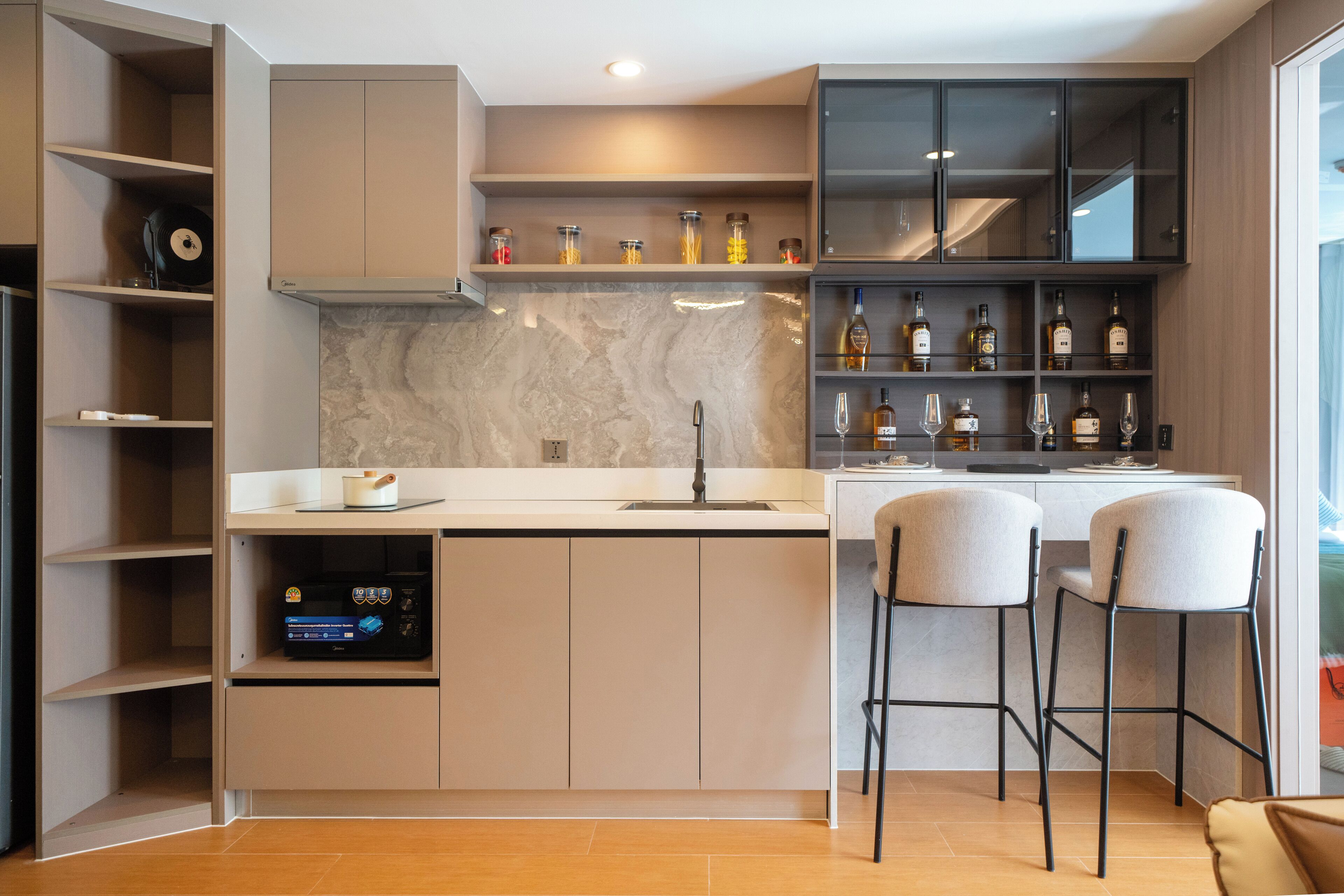 Een moderne keuken met een marmeren achterwand, een ingebouwde bar met krukken, en een wijnrek.