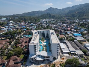 Ein Hotel mit Pool, mehreren Etagen und Blick auf die umliegende Wohngegend.