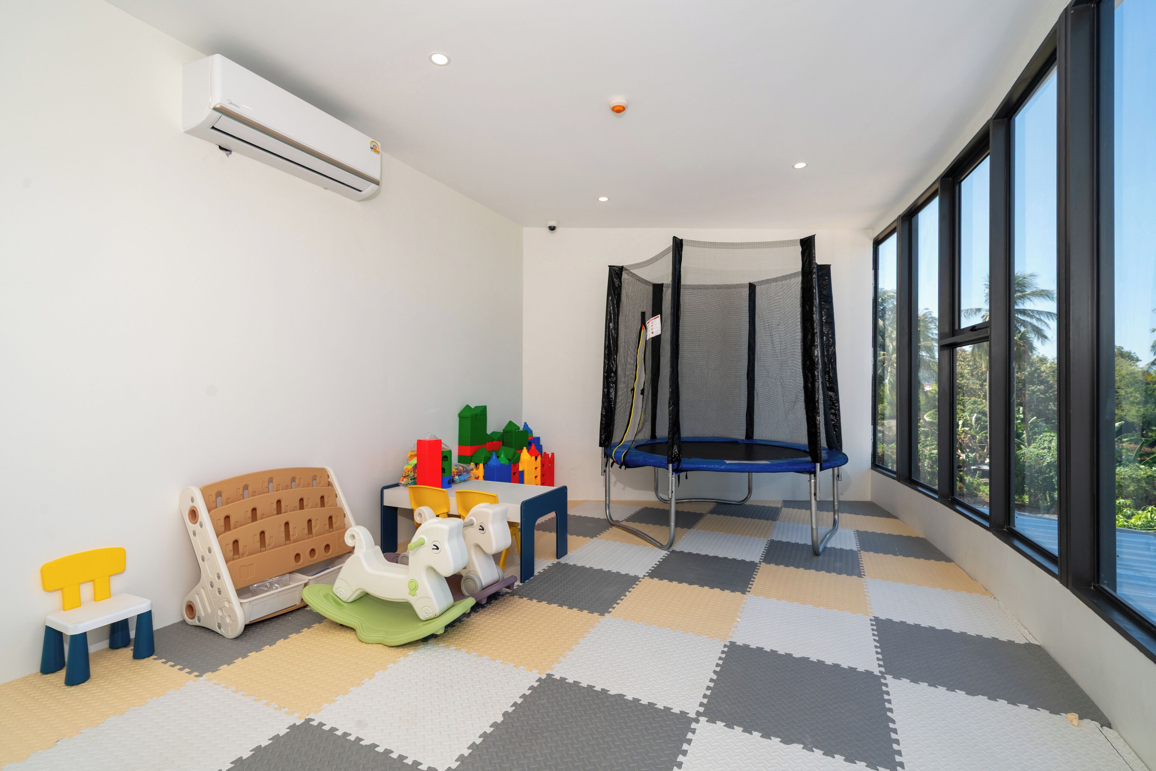 A children's playroom with a trampoline, playpen, and various toys.
