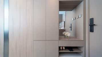 Une chambre moderne et minimaliste, dotée de rangements intégrés, d’un miroir et d’une étagère où sont disposés des objets décoratifs.